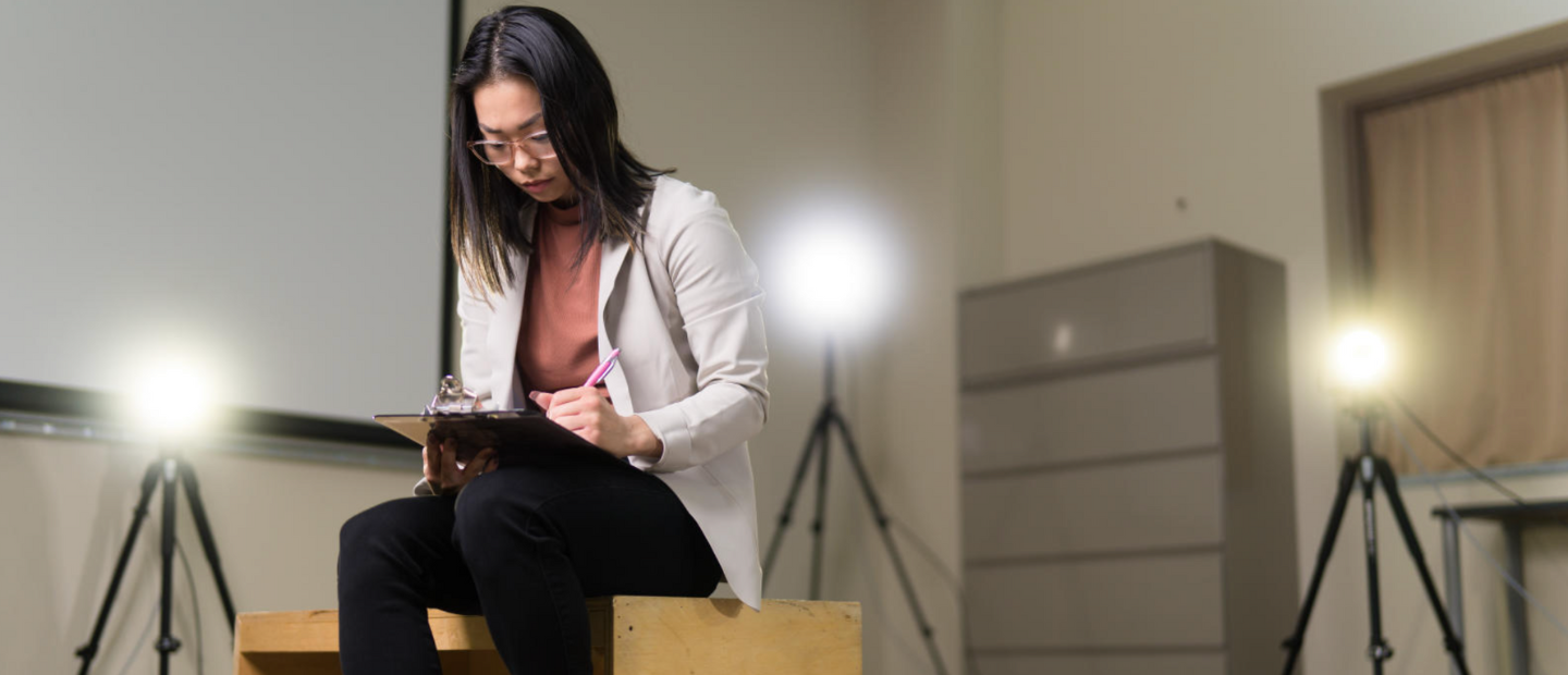 Person in lab coat sitting and writing