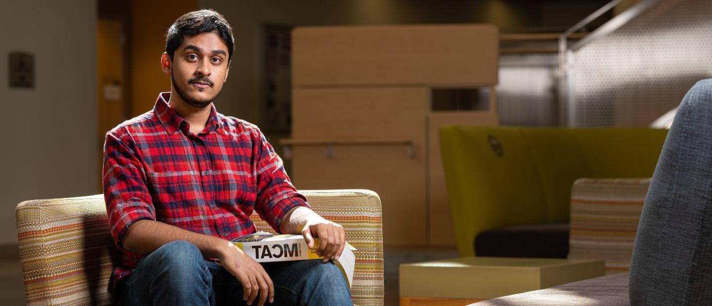 A man sitting in a chair, looking at the camera.