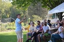 Person teaching group of people outside by a field and a tent