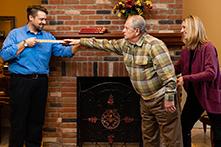 Two physical therapists assist and measure an elderly man as he reaches his arm