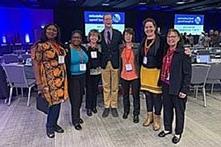 Group of adults at a conference, posing for a photo.